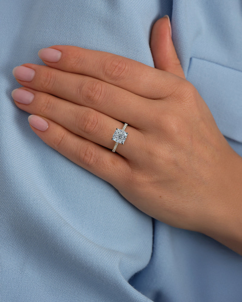 Two tone cushion cut diamond engagement ring worn on hand, featuring platinum head and channel set band 18kt yellow gold by Layla Diamonds