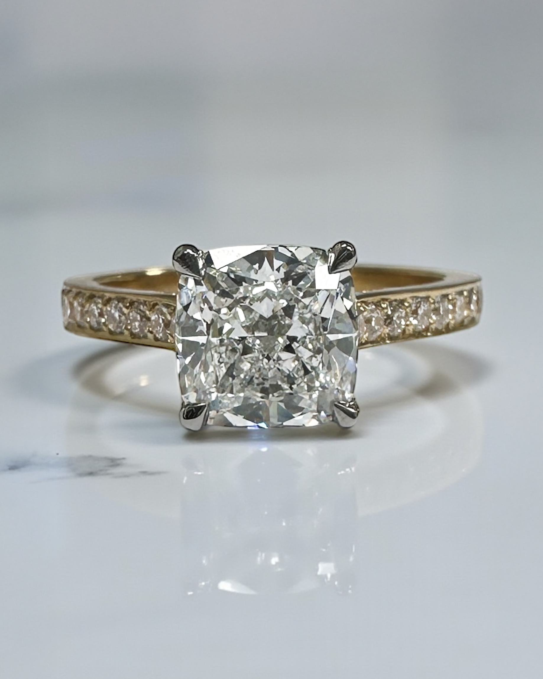 Two tone cushion cut diamond engagement ring, featuring platinum head and channel set band 18kt yellow gold by Layla Diamonds