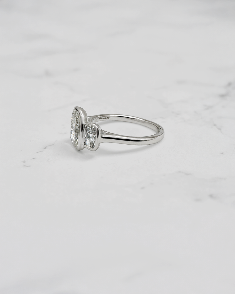 3ct elongated cushion cut lab grown diamond trilogy engagement ring with two 1ct side stones, bezel set rub over setting in polished white metal, handcrafted in London