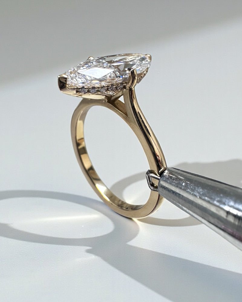 Marquise diamond solitaire ring featuring a hidden halo setting in white gold