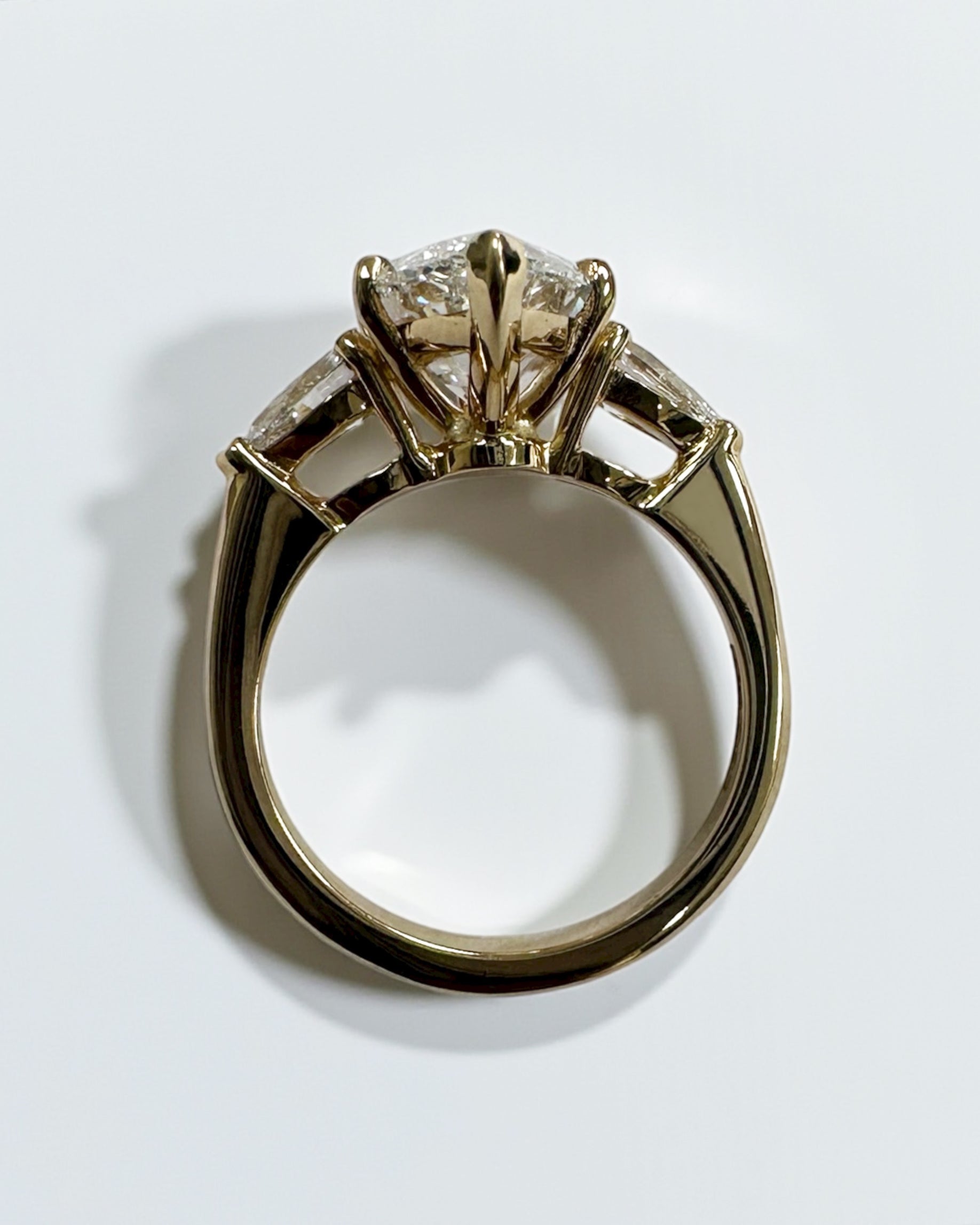 Side view of 3ct marquise cut diamond trilogy ring with pear cut side stones in 18kt yellow gold, showcasing elegant tapered setting and exceptional craftsmanship