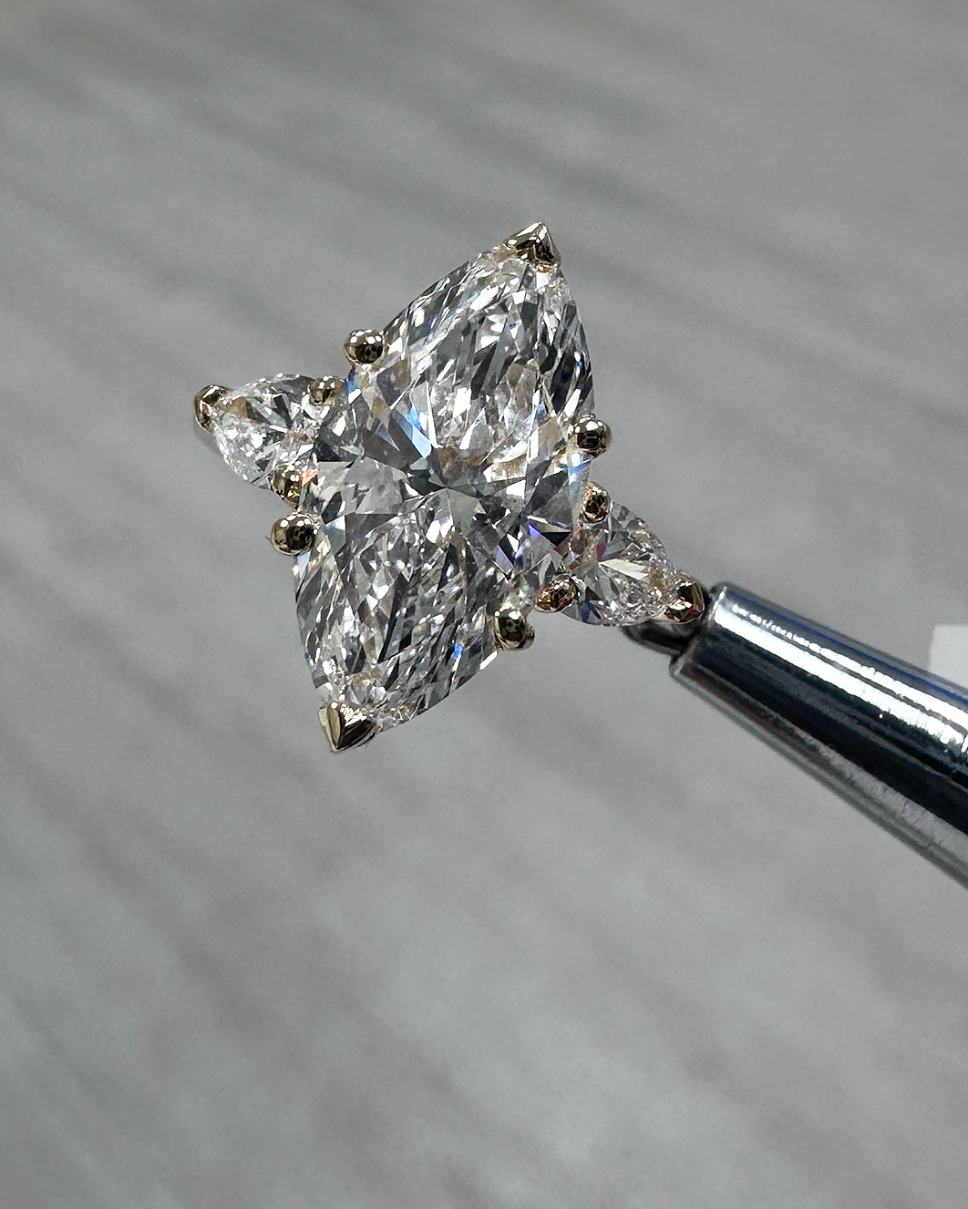 Close-up of pear cut side diamonds framing the marquise centre stone in 18kt yellow gold setting, highlighting precision and fine detailing