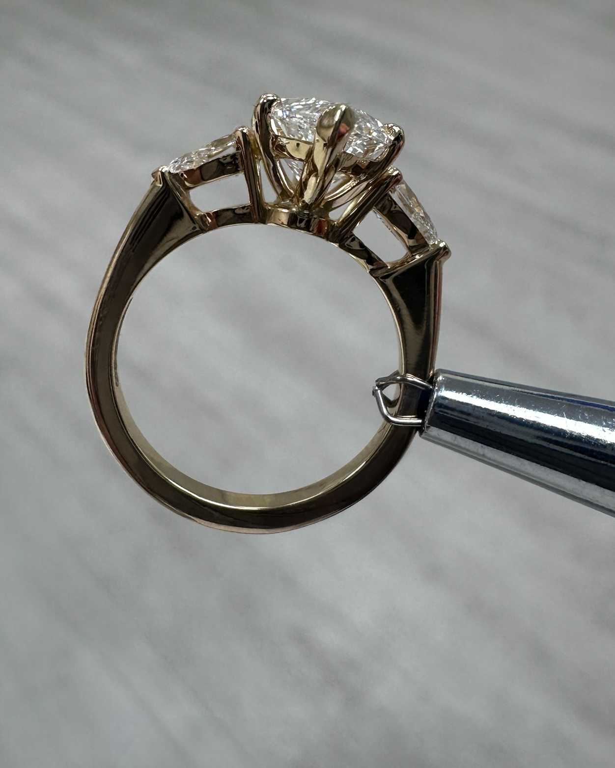 Side view of 3ct marquise cut diamond trilogy ring with pear cut side stones in 18kt yellow gold, showcasing elegant tapered setting and exceptional craftsmanship