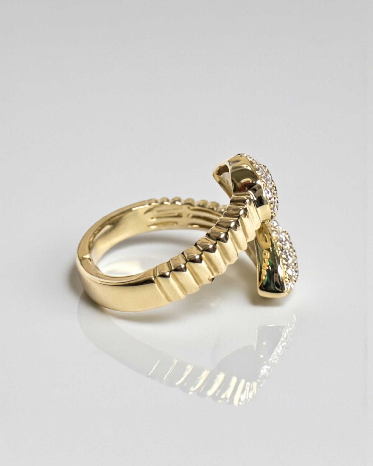Side view of serpent wrap diamond ring showing ribbed gold band and pear shaped diamond pavé ends, 9ct gold.