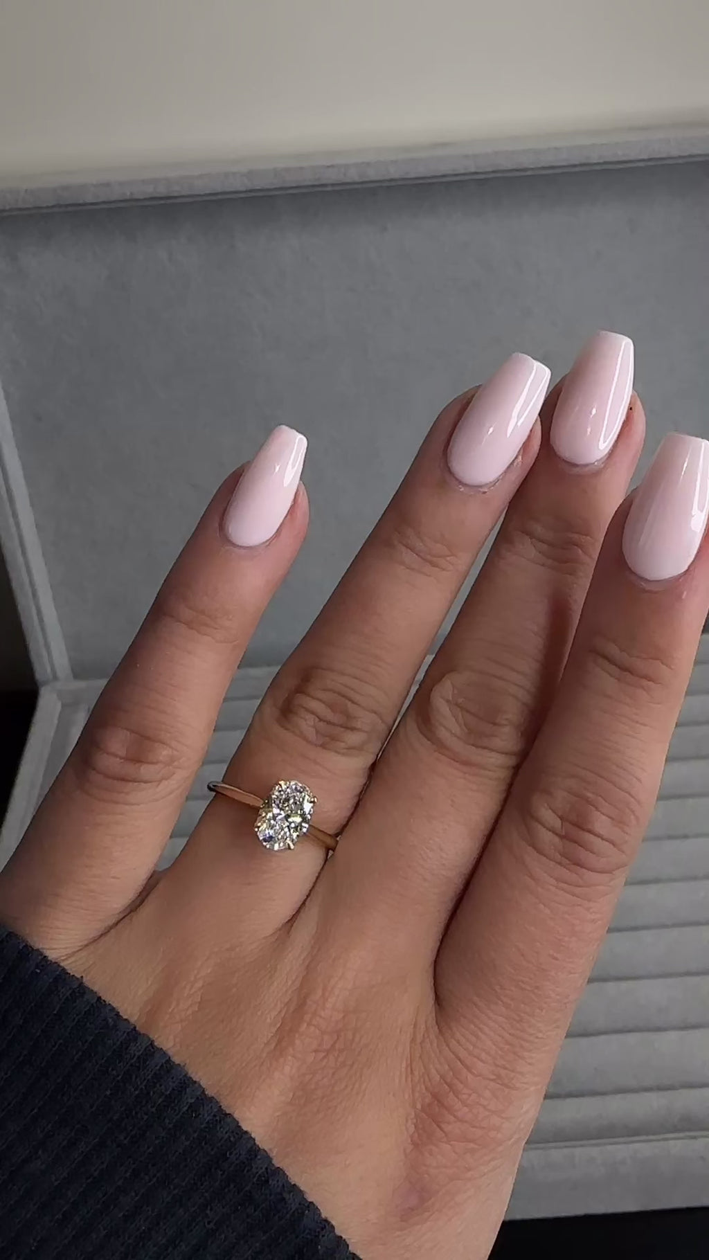 Close up of oval diamond engagement ring with hidden pavé bridge and cathedral setting on hand