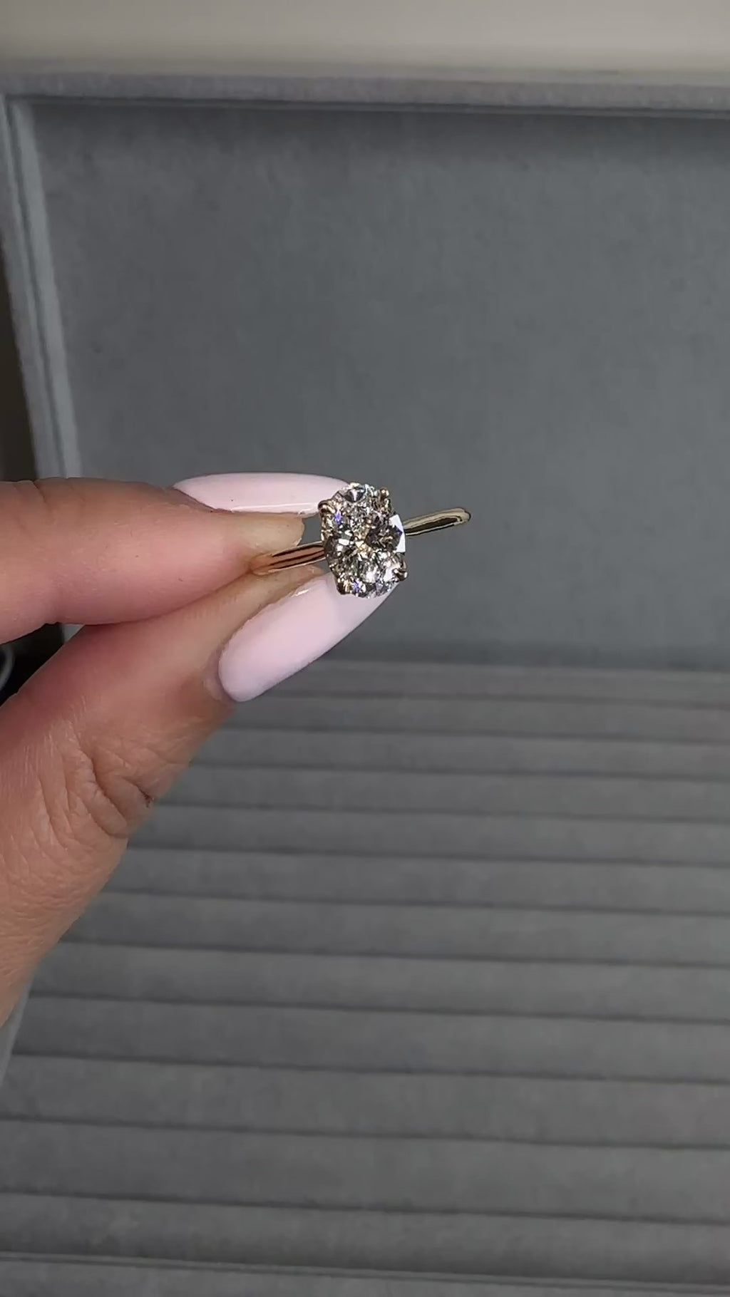 Close up of oval diamond engagement ring with hidden pavé bridge and cathedral setting