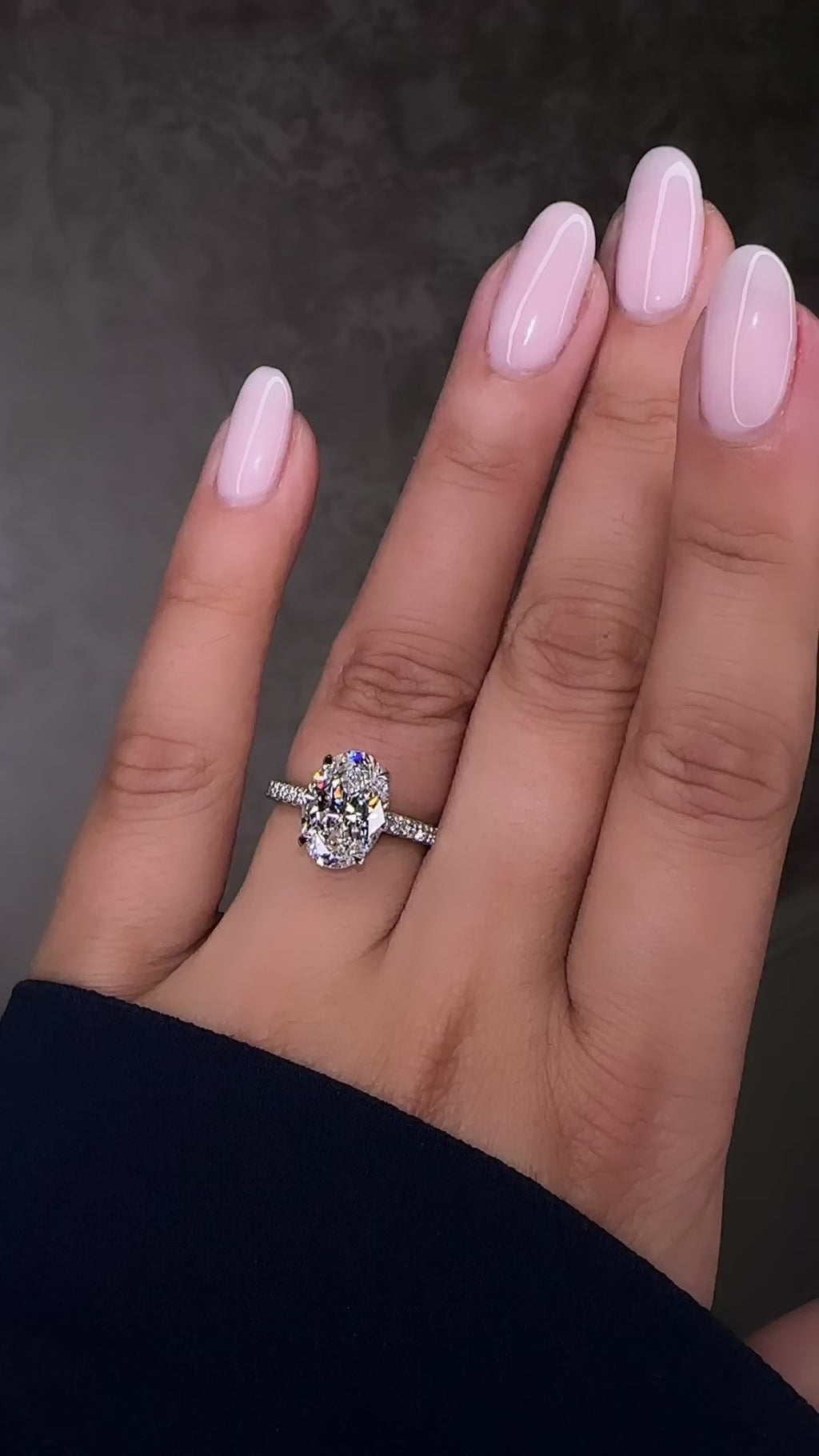 3.50ct oval cut lab grown diamond cathedral hidden halo engagement ring with diamond set shoulders and diamond bridge in platinum on hand
