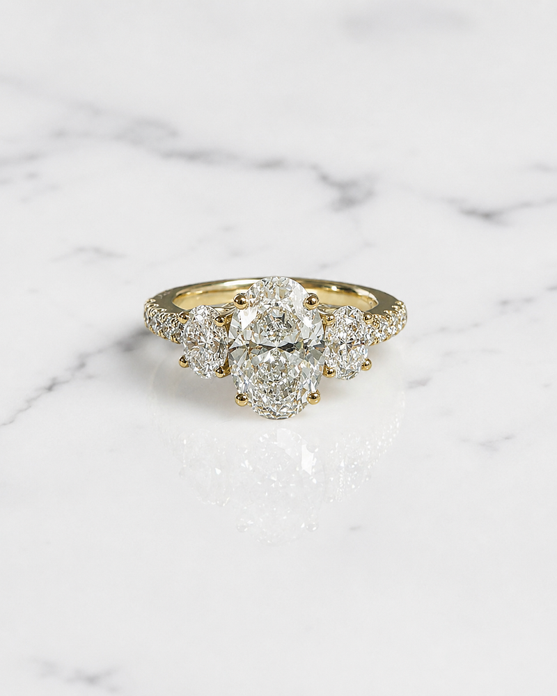 2.90ct oval cut lab grown diamond trilogy engagement ring with 2ct centre diamond, oval side stones and diamond set shoulders in yellow gold