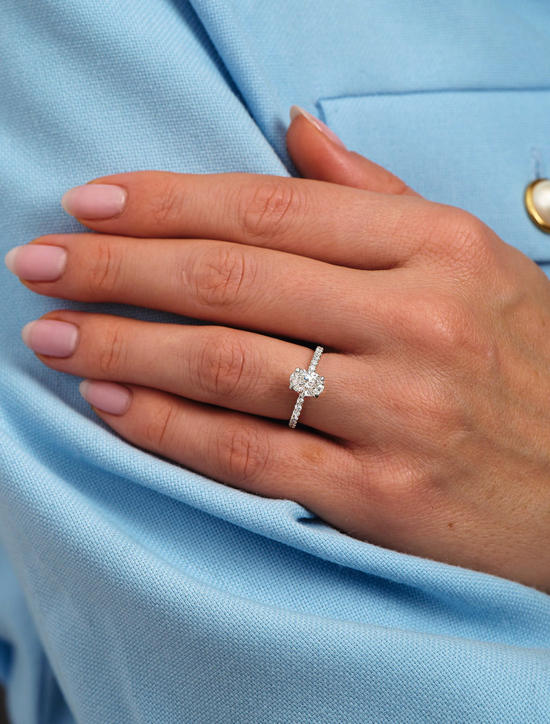 1ct oval cut lab grown diamond hidden halo engagement ring on hand with diamond shoulders by Layla Diamonds
