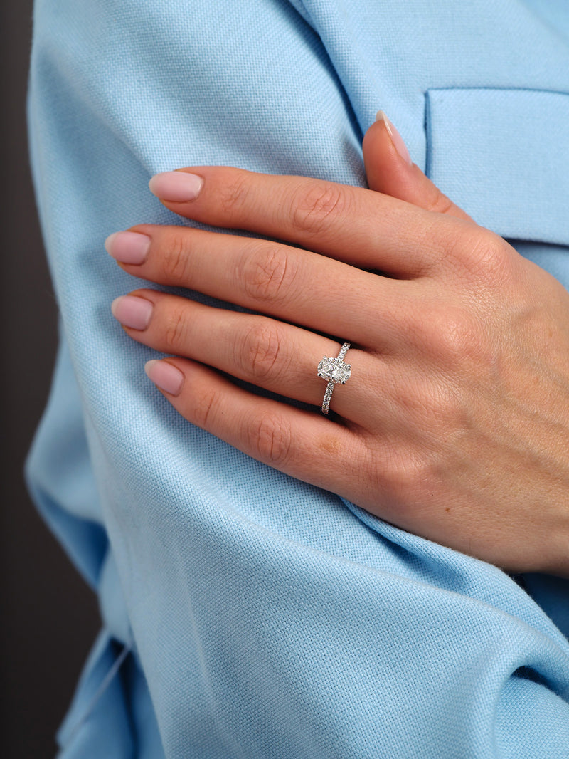 1.50ct oval cut lab grown diamond hidden halo engagement ring on hand with diamond shoulders by Layla Diamonds.