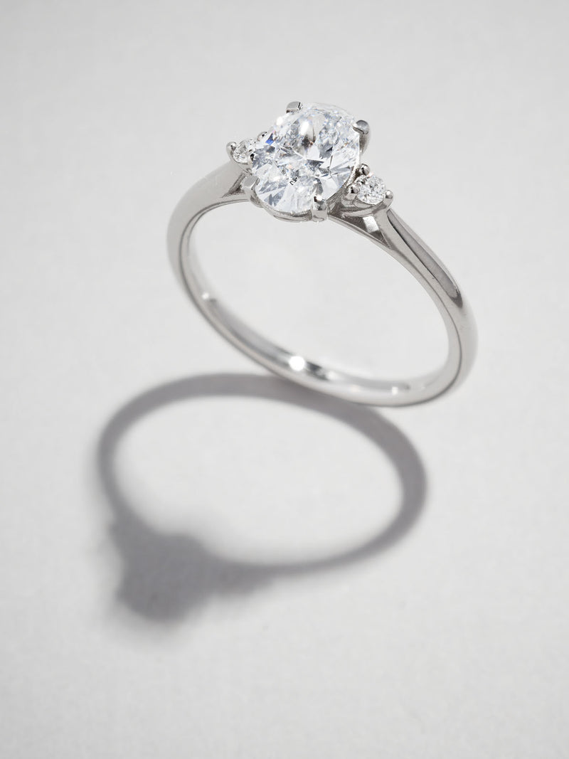 1ct oval cut lab grown diamond trilogy engagement ring with round brilliant side diamonds and cathedral band by Layla Diamonds.