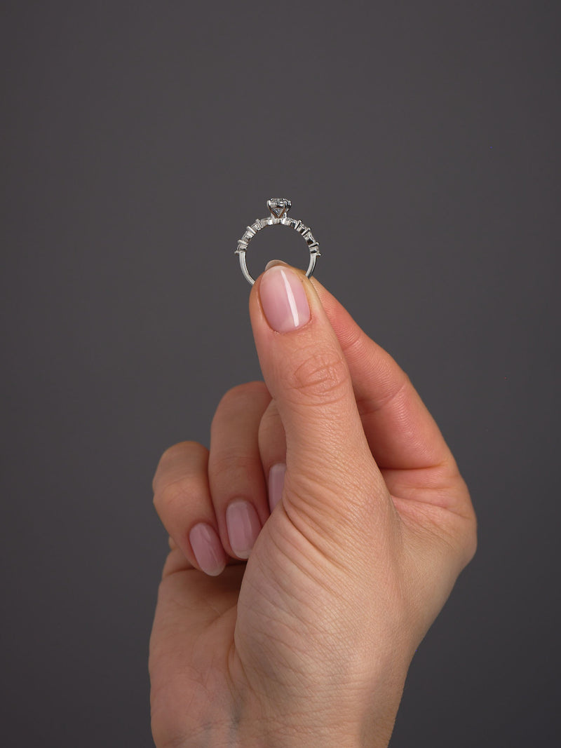 1ct oval cut lab grown diamond engagement ring on hand with marquise and round diamond band by Layla Diamonds.