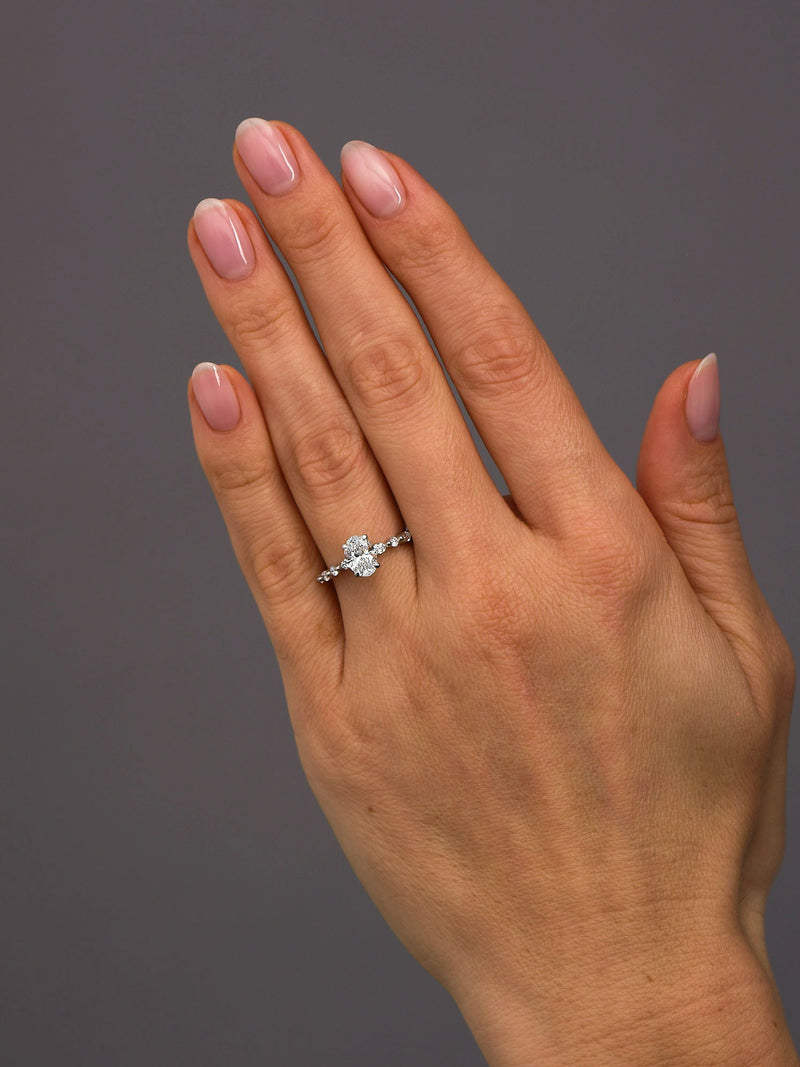 1ct oval cut lab grown diamond engagement ring with marquise and round diamond band on hand by Layla Diamonds.