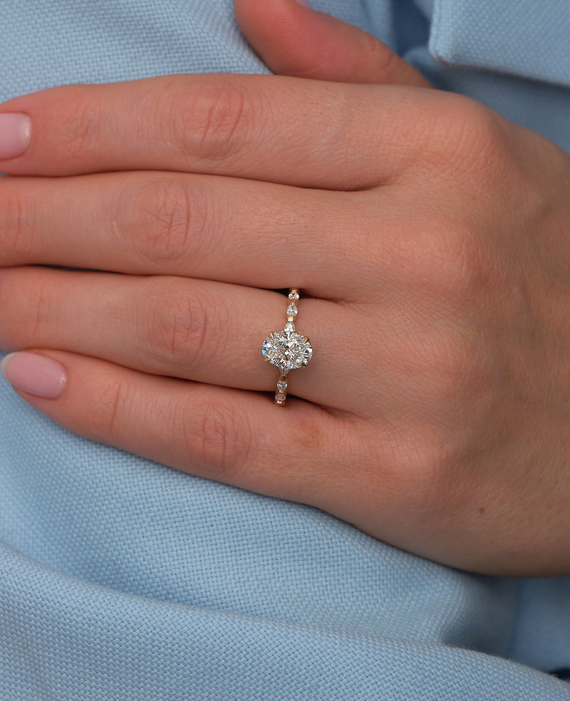 1.50ct oval cut lab grown diamond engagement ring on hand with marquise and round diamond band and hidden halo by Layla Diamonds.