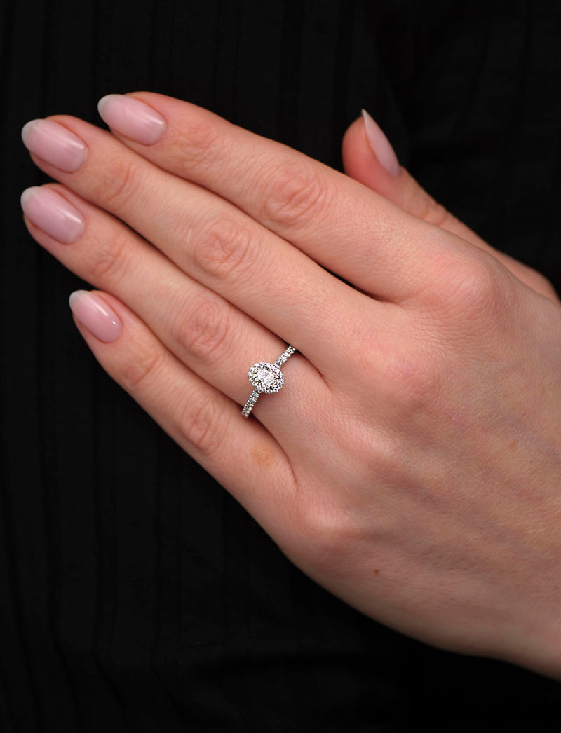 0.35ct oval cut lab grown diamond seamless halo engagement ring on hand with diamond shoulders by Layla Diamonds.