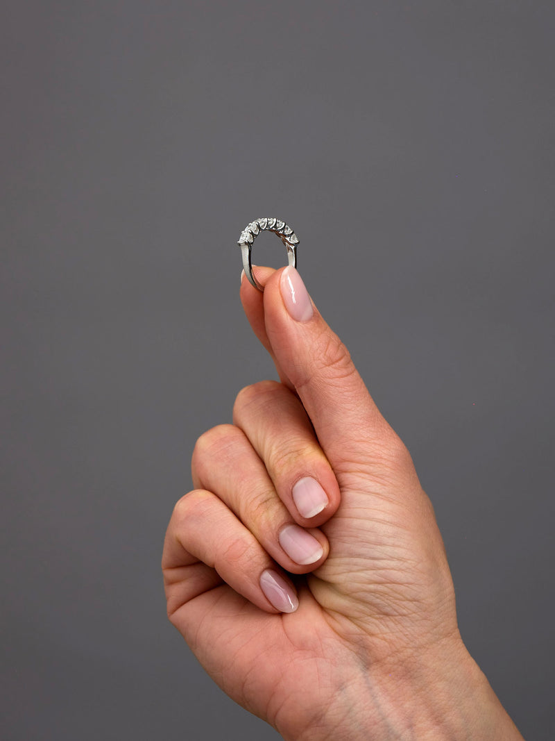 Cushion cut diamond eternity band worn on a finger, showcasing a classic and sophisticated diamond engagement band design.
