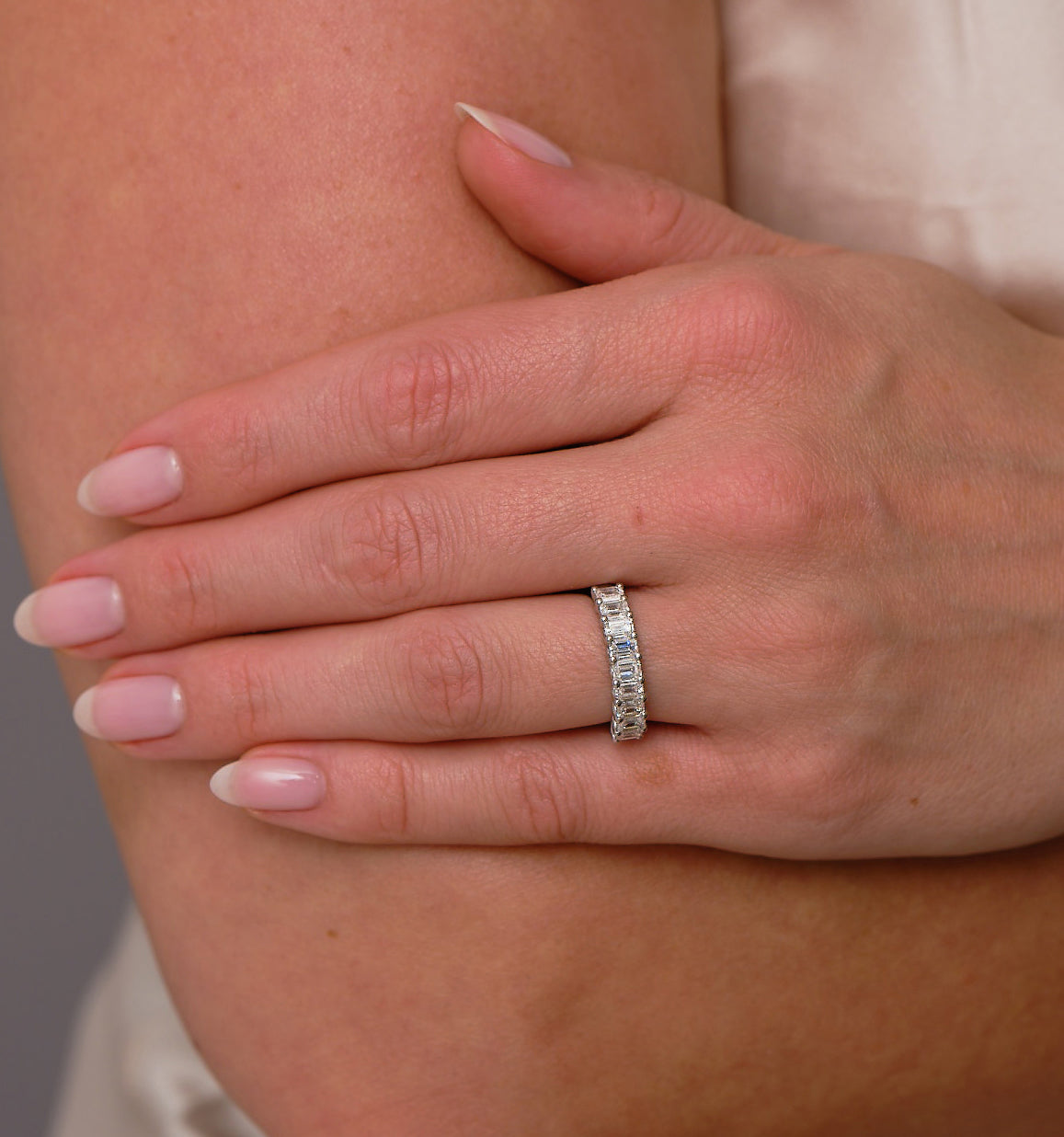 1.4ct emerald cut diamond band worn on a finger, matching with diamond engagement rings.