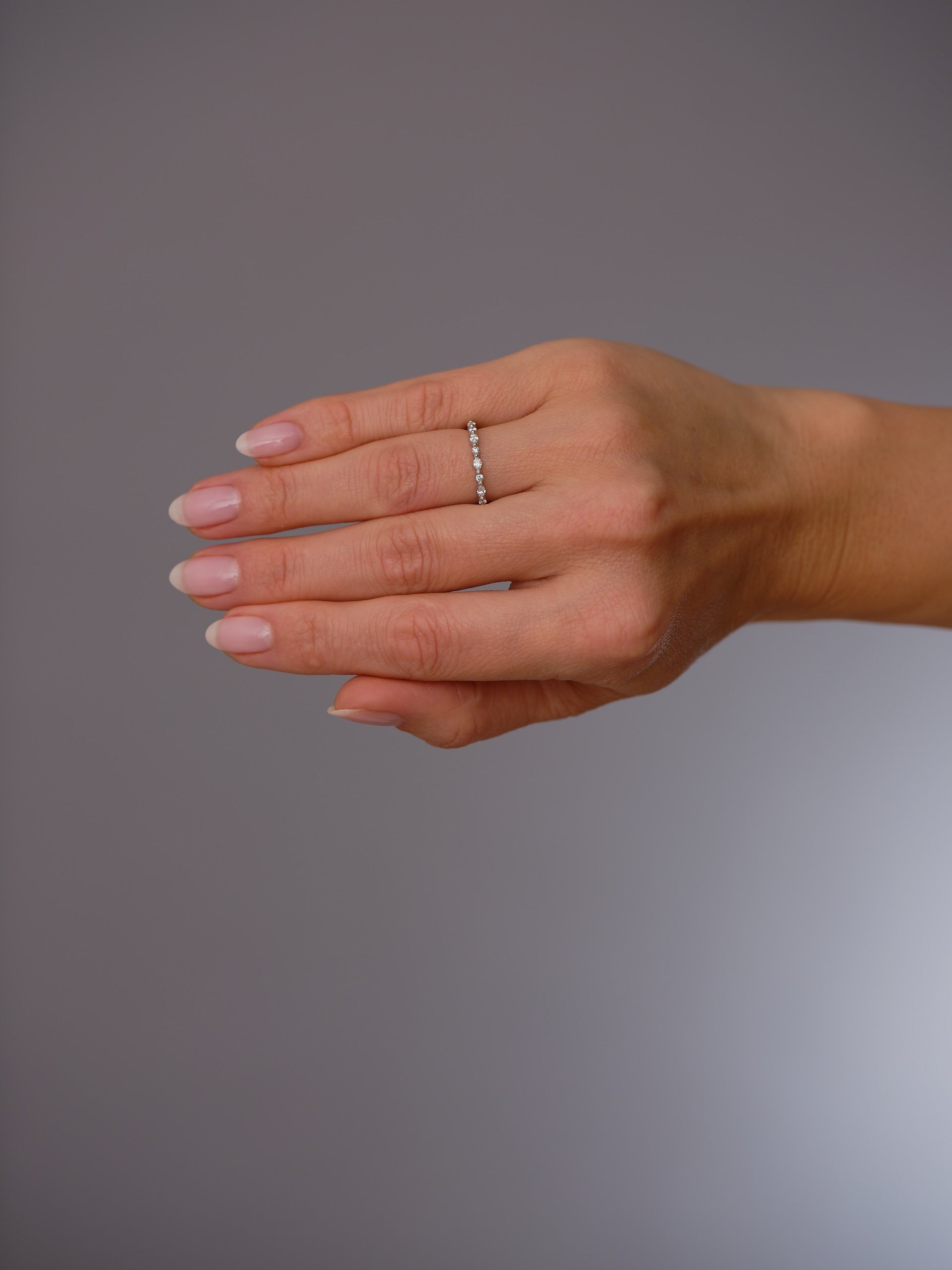 Marquise and round diamond eternity band worn on a finger, showcasing diamond wedding bands style.