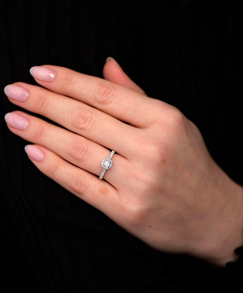 A cushion cut seamless halo ring worn on a finger, featuring a marquise engagement ring diamond style.